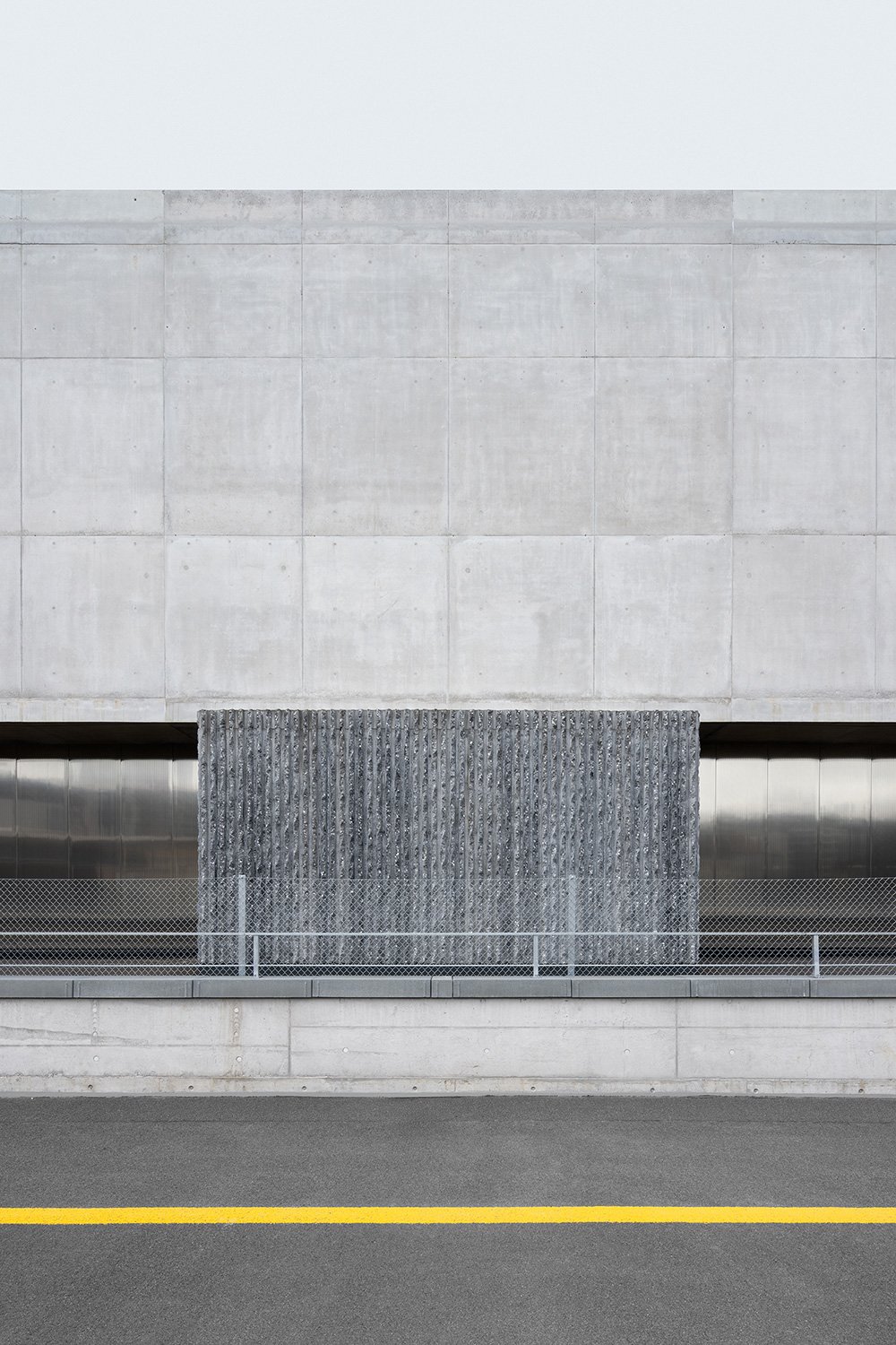 Grafische Fassadenaufnahme der SGKB Halle St. Gallen mit skulpturalem Betonpfeiler von Ilg Santer Architekten.
