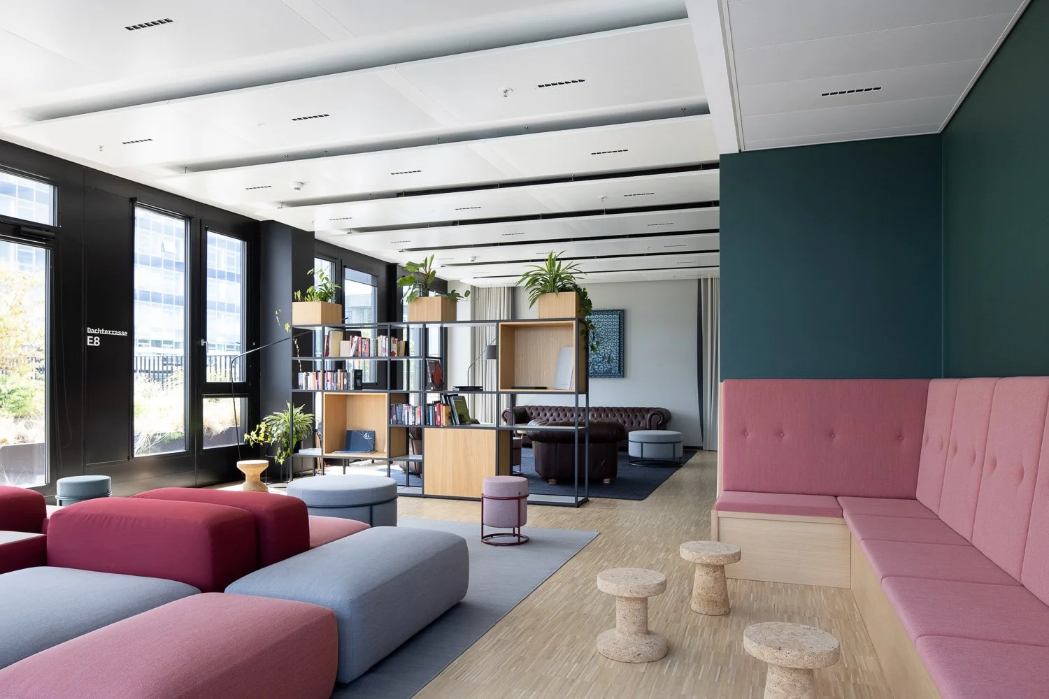 Interior Design Fotografie einer moderne Office-Lounge mit farbigen, modularen Möbeln, einer integrierten Sitzbank und den Vitra Cork Family Hockern von Jasper Morrison.