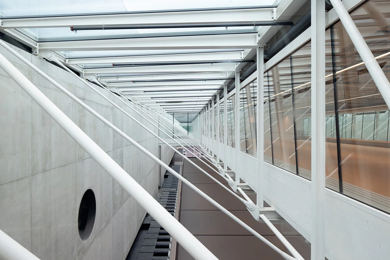 Perspektivische Innenraumaufnahme der Stahlkonstruktion im Foyer der SGKB Halle St. Gallen unterhalb des Glasdachs mit rhythmischer Tragstruktur und natürlicher Lichtführung.
