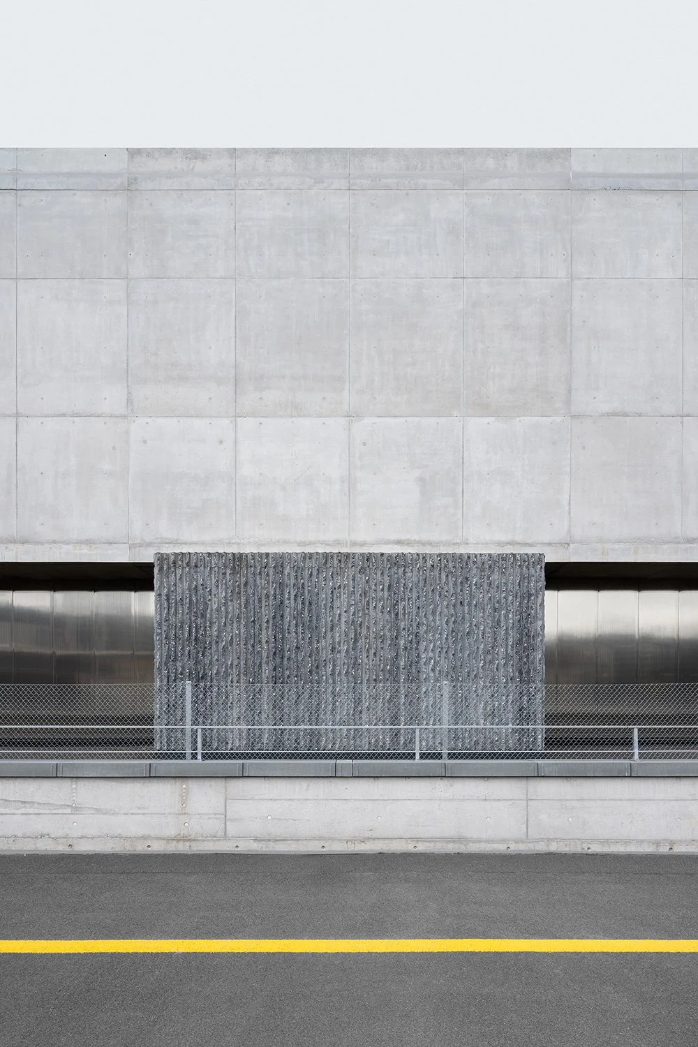 Grafische Fassadenaufnahme der SGKB Halle St. Gallen mit skulpturalem Betonpfeiler von Ilg Santer Architekten.
