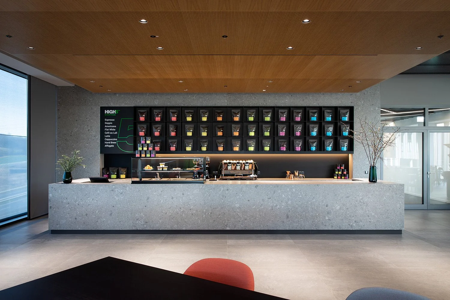 Moderner Coffee-Bar- und Thekenbereich der High5 Gastronomie in der Engelbert Strauss CI Factory in Schlüchtern mit Naturstein, Holz und sichtbarer Siebträgermaschine.
