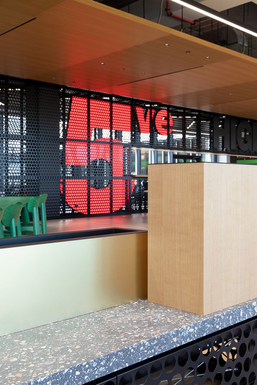 Detailaufnahme freistehender Raum-Trennelemente im High5 Gastronomiebereich der Engelbert Strauss CI Factory mit perforierten Metallstrukturen und Terrazzo-Oberflächen.
