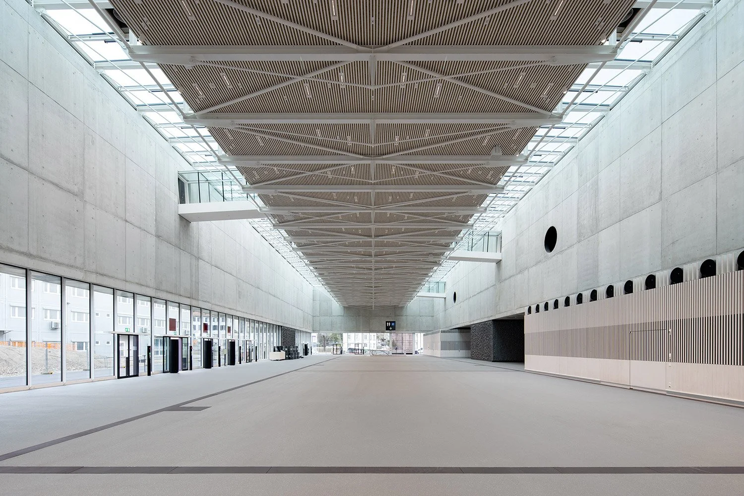 Zentralperspektivische Innenraumaufnahme des lichtdurchfluteten Foyers der SGKB Halle St. Gallen mit stützenfreier Architektur und markanter Dachkonstruktion.
