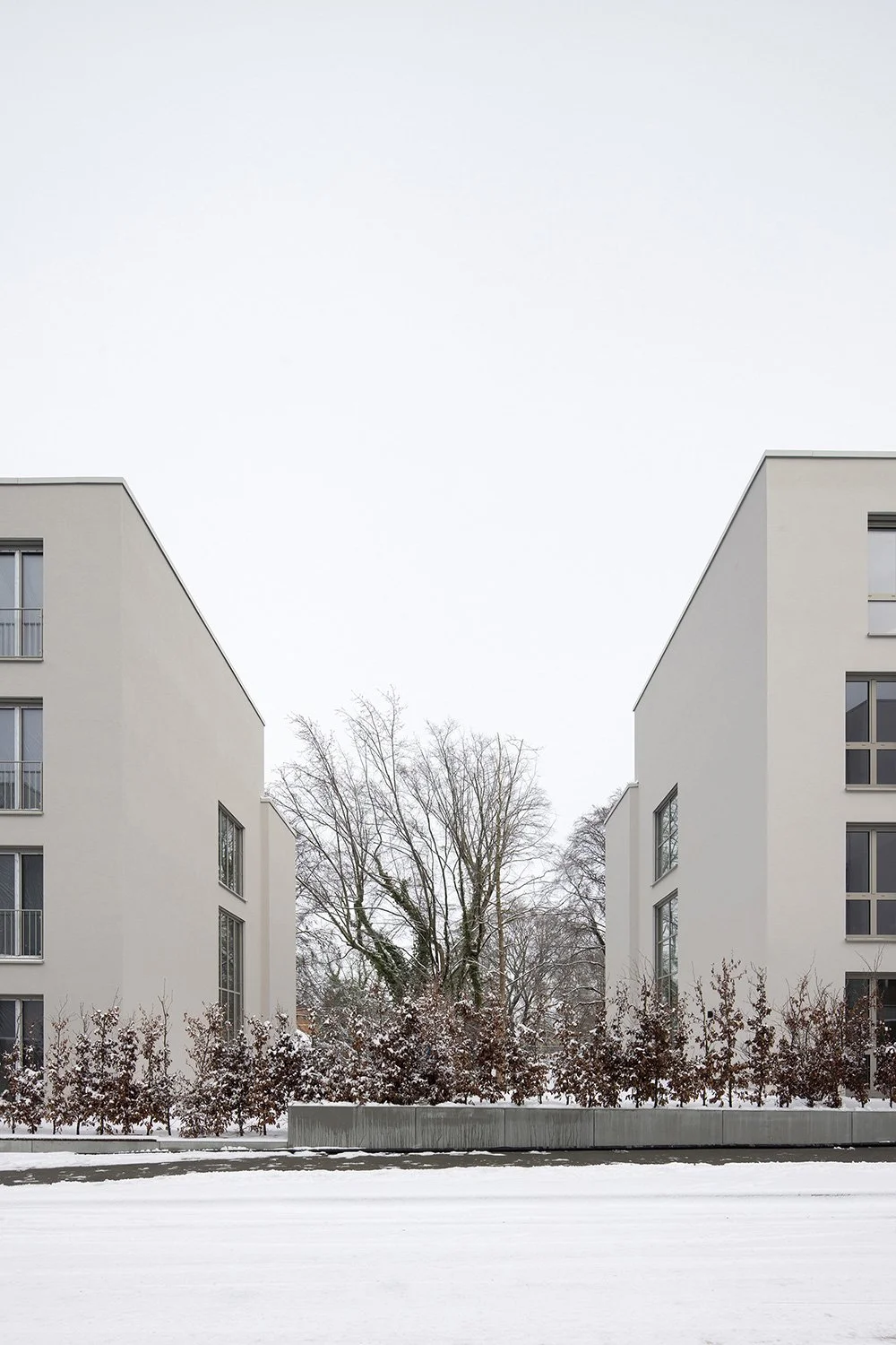 Hochformatige Architekturfotografie der Wohnhäuser am Schubertschen Park mit zurückhaltender Fassadengestaltung, seitlichem Gebäudeabstand und winterlicher 
