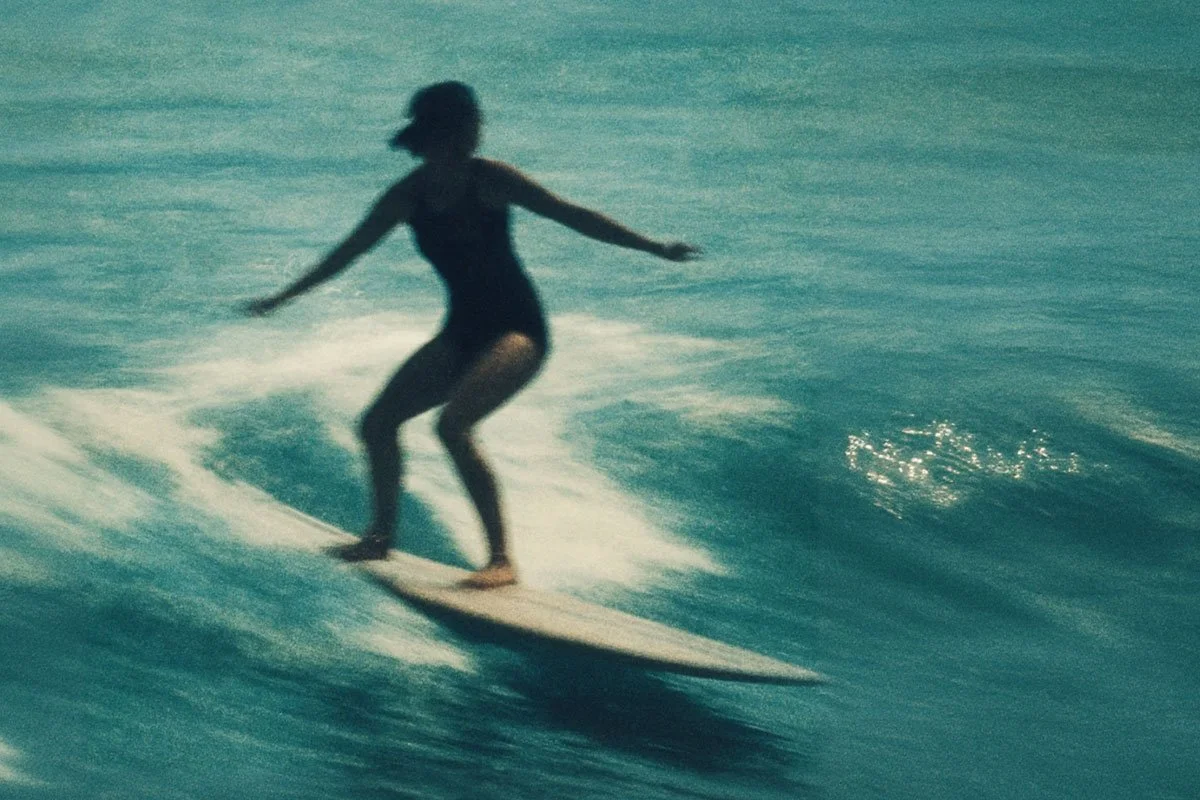1960s woman surfing California. Retro vibe photo by 1923 Main Street.