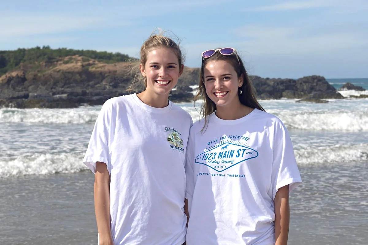 Girls on the beach in white cotton t-shirts.