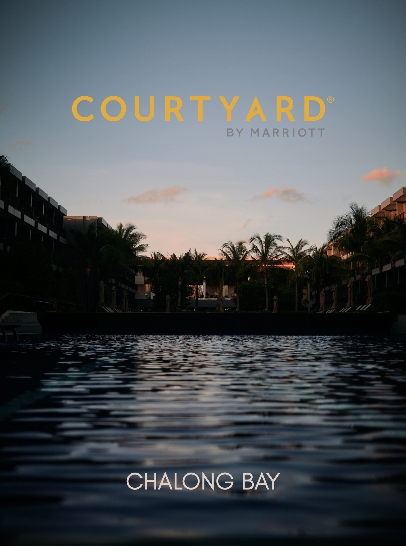 Sunset view over water with palm trees and buildings, featuring the text 'Courtyard by Marriott' and 'Chalong Bay'.