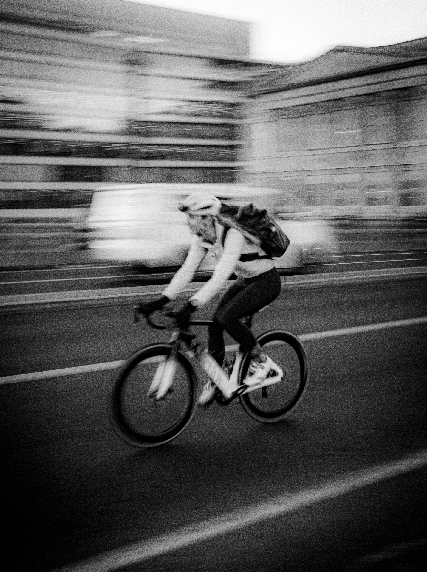 A person riding a bicycle on a city street in motion blur, with buildings and other urban elements in the background.