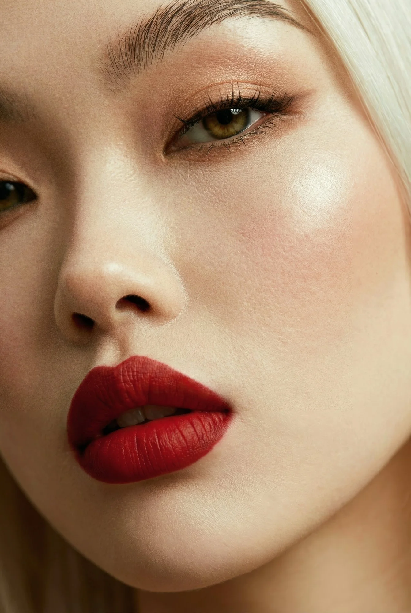 Extreme close-up beauty portrait of a model with red lipstick, detailed skin texture, visible pores and controlled studio lighting.