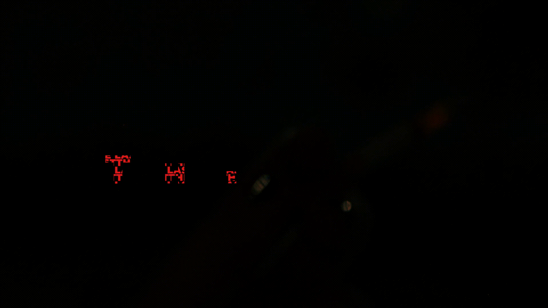 Nighttime view of a road with illuminated red digital signs displaying the speed limit, and a car's hand and part of the steering wheel visible in the foreground.