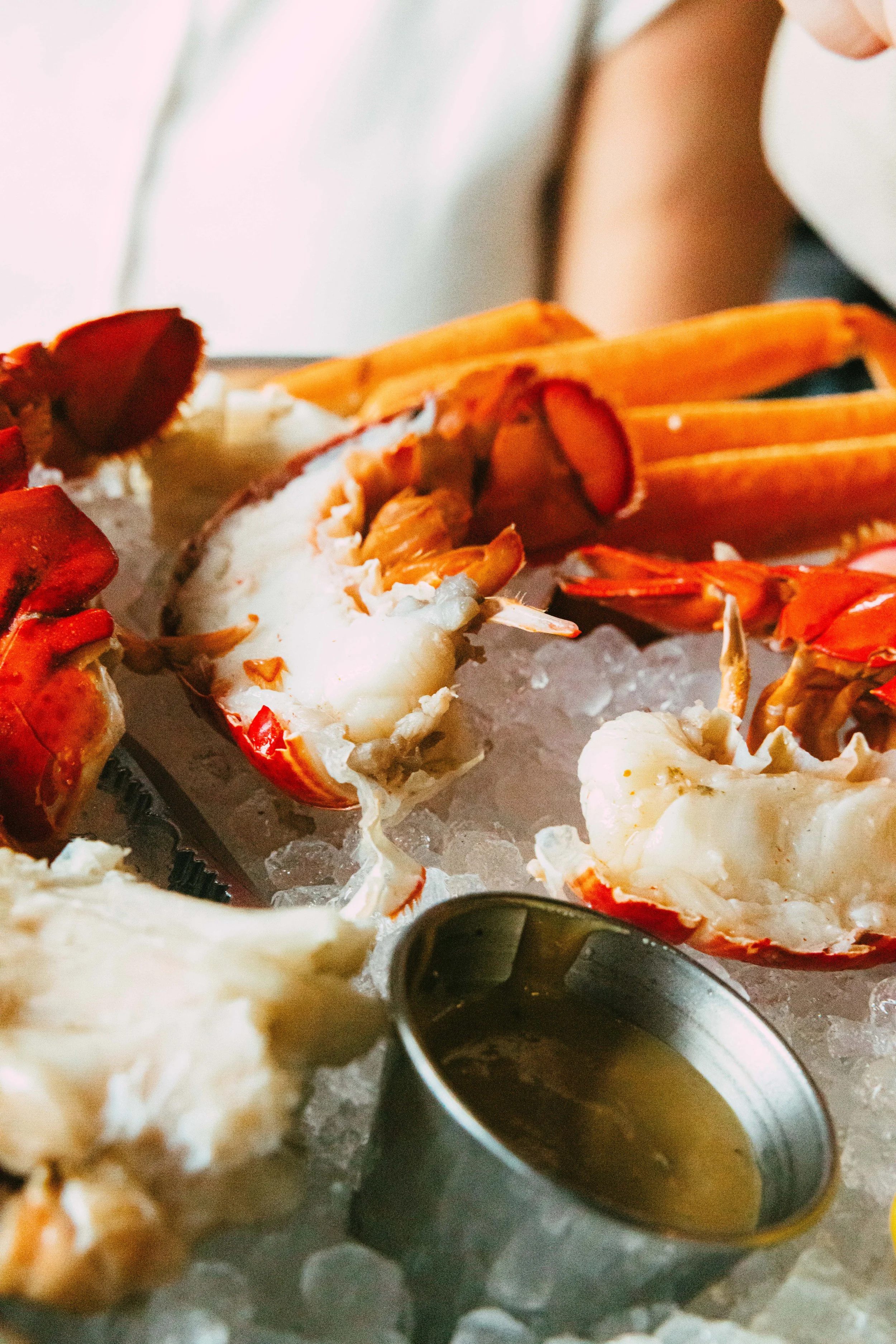 Lobster tails on ice with melted butter in a metal cup
