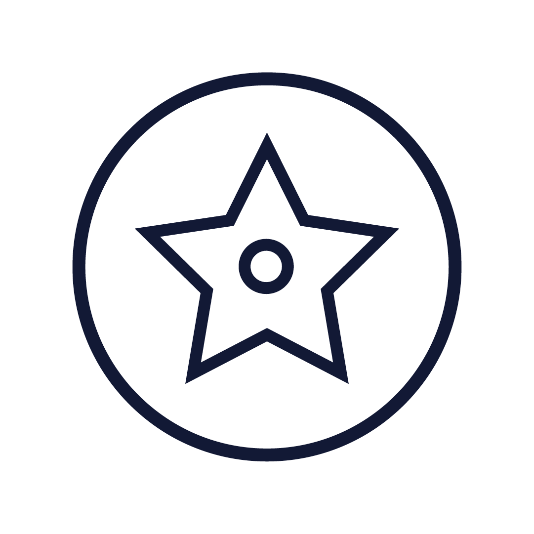 A man with short, wavy dark hair, clear plastic glasses, a nose ring, and a beard, wearing a black sweater, sitting indoors with a neutral expression, and a green plant in the background.