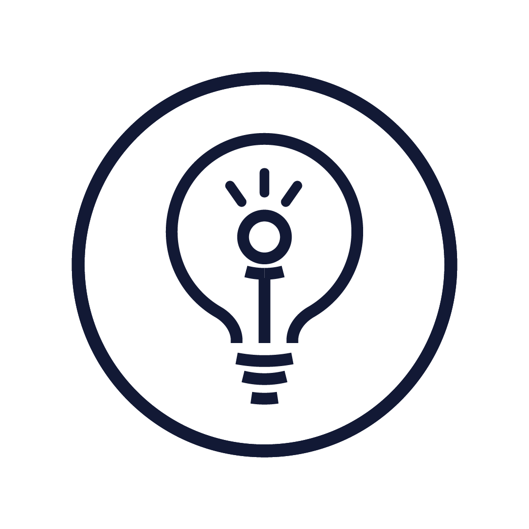 A smiling woman with curly hair wearing glasses, hoop earrings, and layered necklaces inside a warmly lit room.