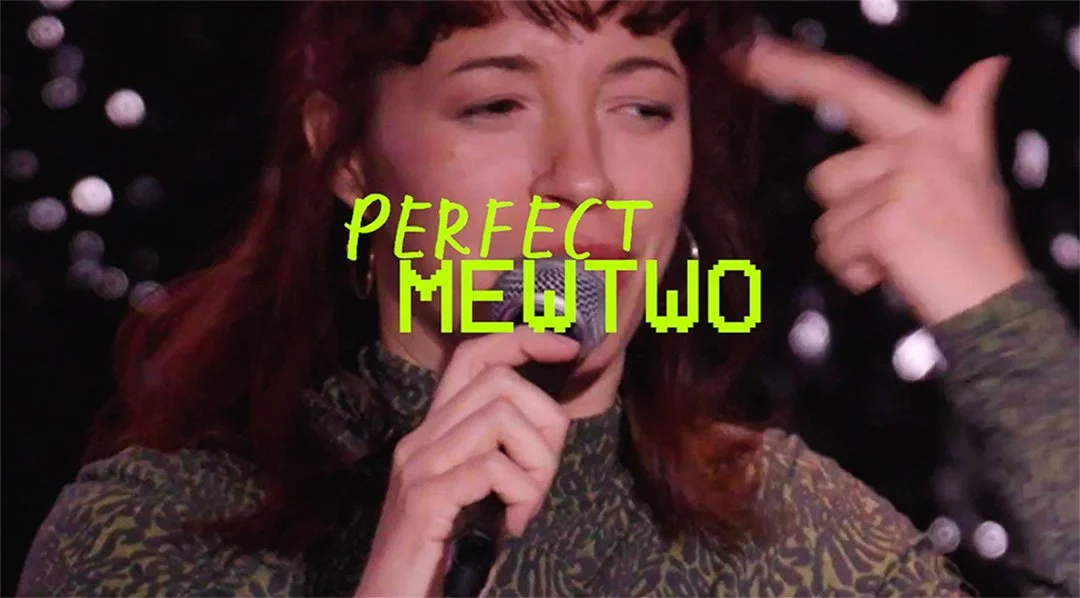 A woman with wavy red hair holds a microphone, touching her head with her left hand, with the words 'PERFECT MEWTWO' in bright green text overlaying the image.