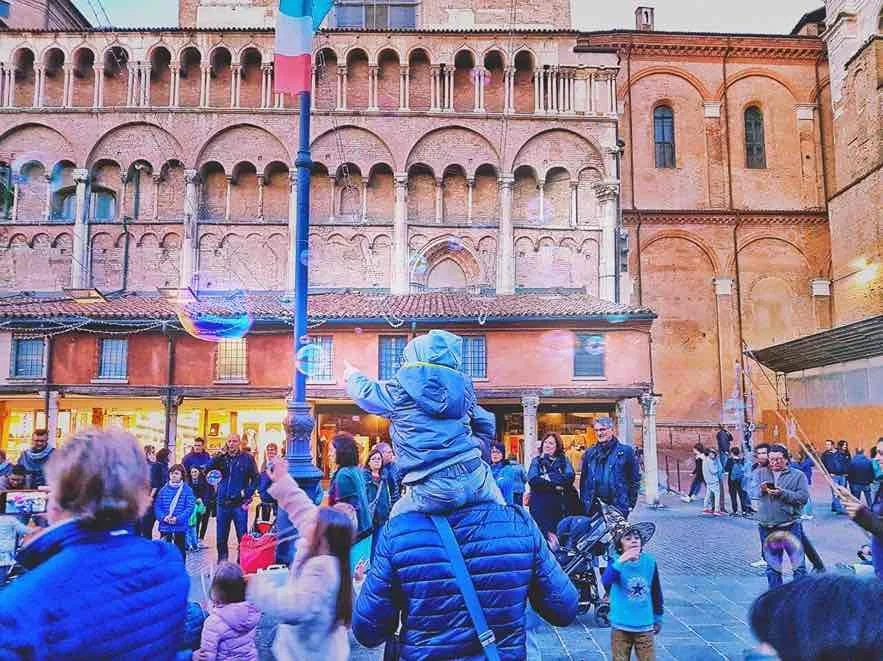 Bambino sulle spalle del papà in piazza a Ferrara tra bolle di sapone e il centro storico