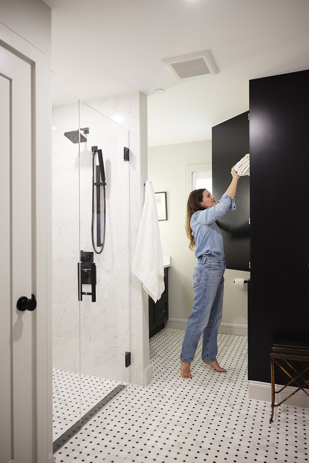 Guest Bathroom After: Laid new tile on the floor, created a graded shower floor with a linear drain and no curb/threshold. We added a built-in linen closet that provides storage and hides the toilet from being the first thing you see upon entering.