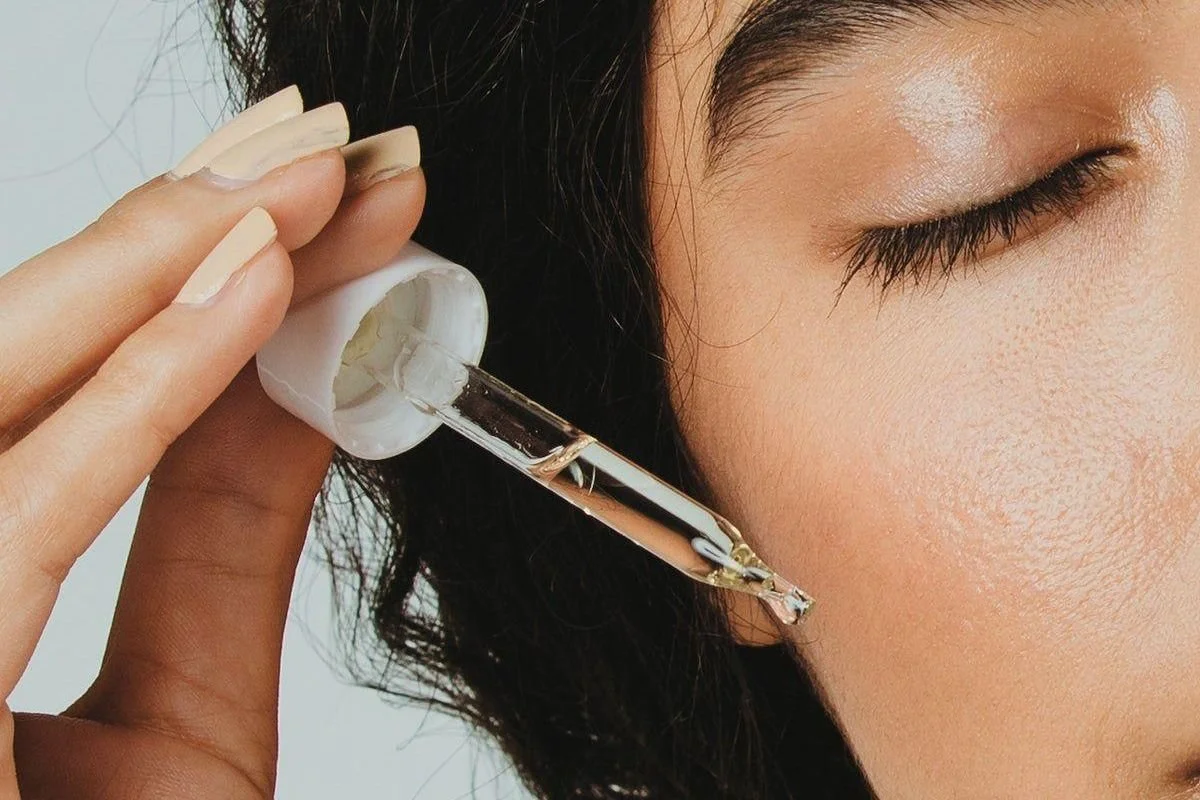 Woman applying a hydrating serum as part of a consistent glass skin skincare routine.