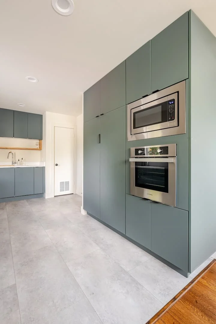 Modern kitchen with blue cabinets, built-in microwave and oven.