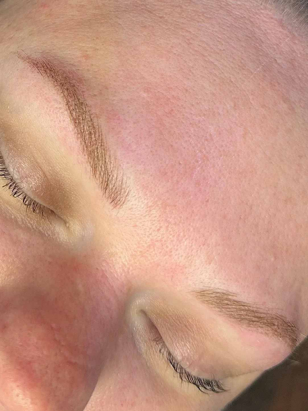 Close-up of a person's face with closed eyes, showing eyebrows, eyelash, and smooth skin.