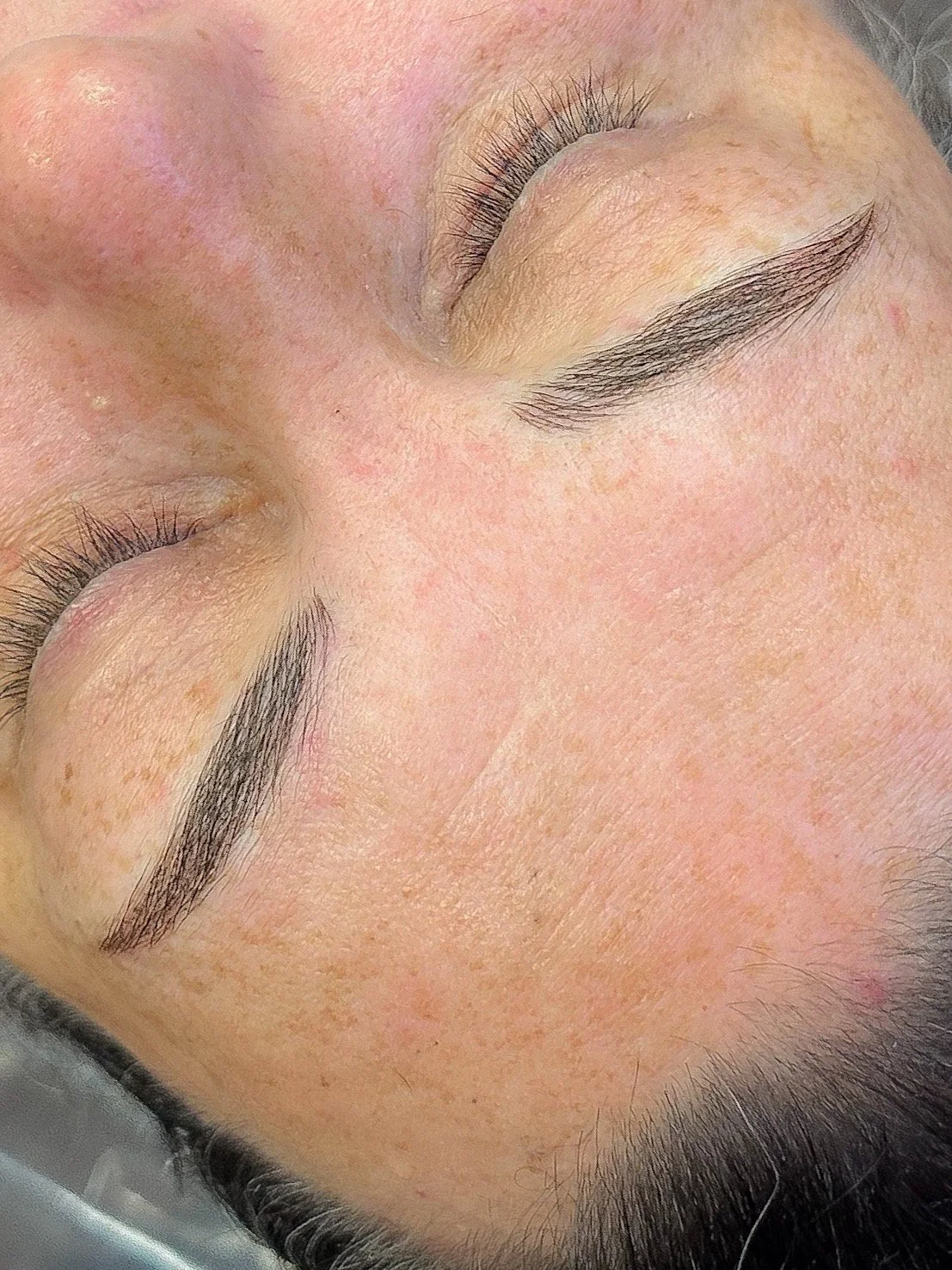 Close-up of a person's forehead and closed eyes, with visible eyebrows and eyelashes.