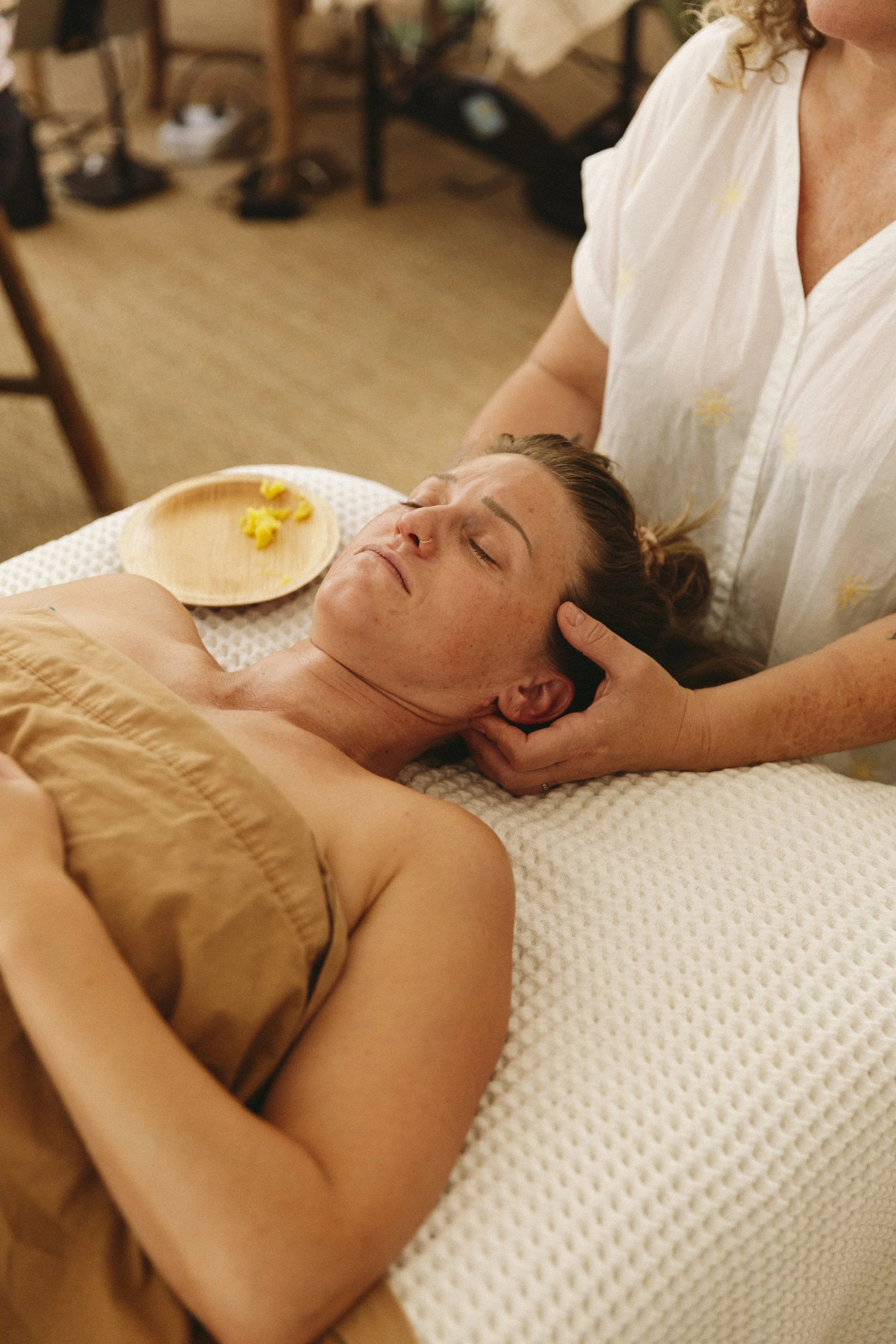 A woman is receiving a massage while lying on a massage table, with her eyes closed and a peaceful expression.
