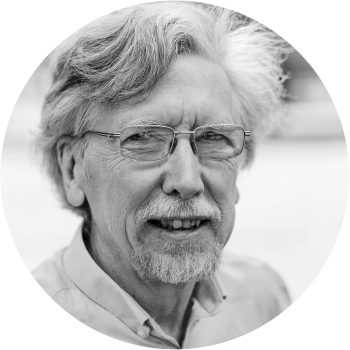Close-up black and white photo of an older man with glasses and gray hair.