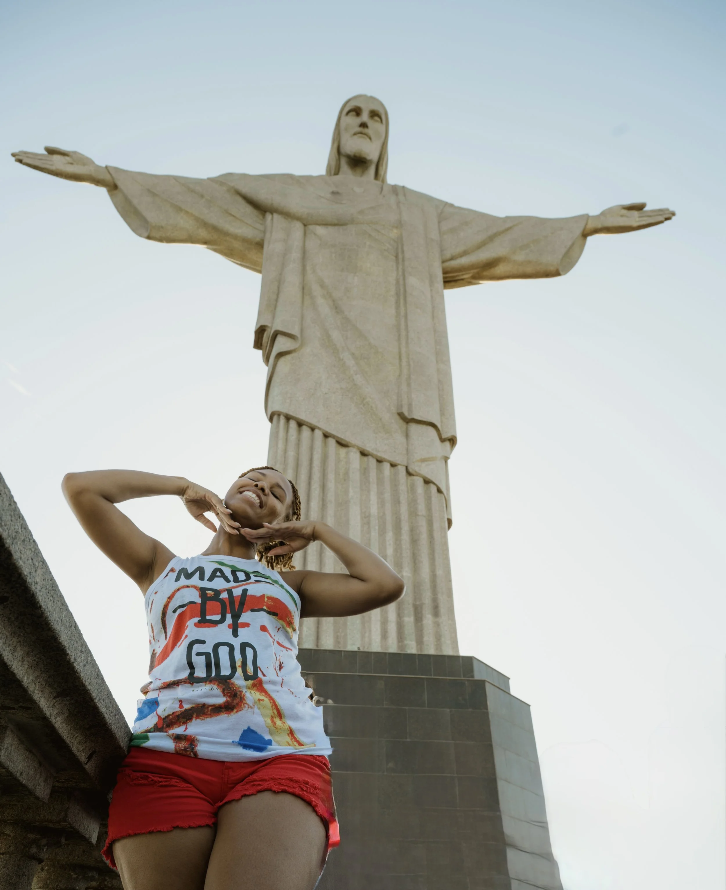 Girl standing in front of Christ, the Redeemer in Rio de Janeiro during Black Consciousness Month, exploring Afro-Brazilian culture and history.