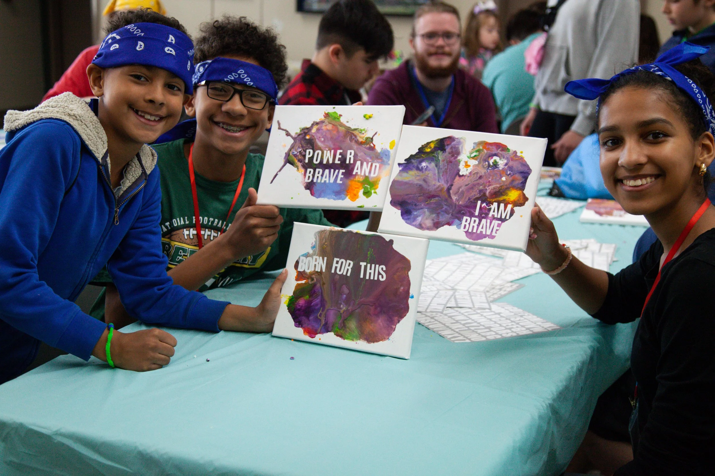 A diverse group of teens sit on the ground, in a circle talking. 