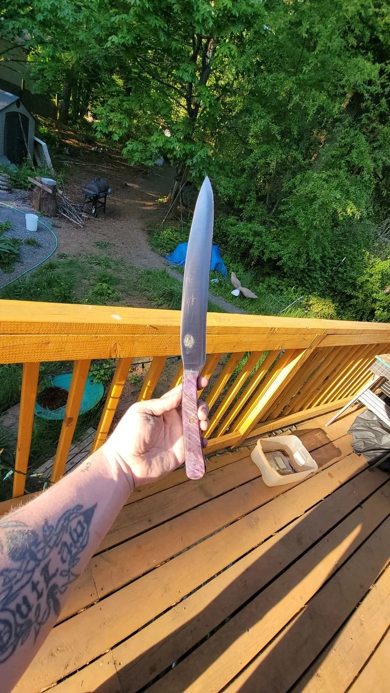 A finished knife held up outdoors