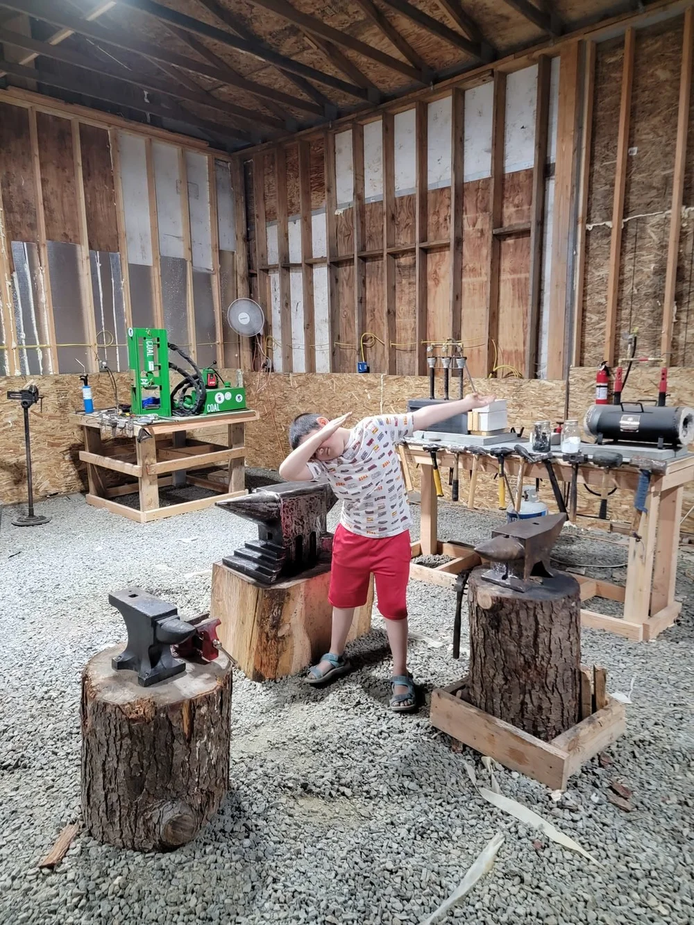 Our first forge in 2021: bare wood walls and stump anvils