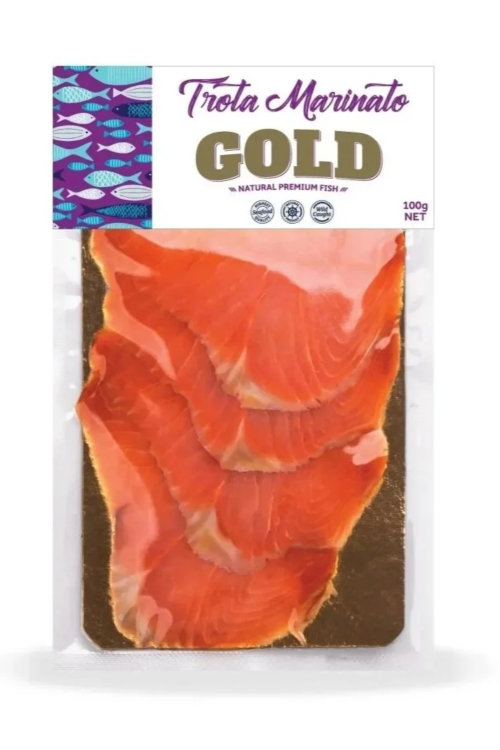 Packaged thinly sliced smoked salmon fish with a label that says Trota Marinato Gold, natural premium fish, 100 grams.