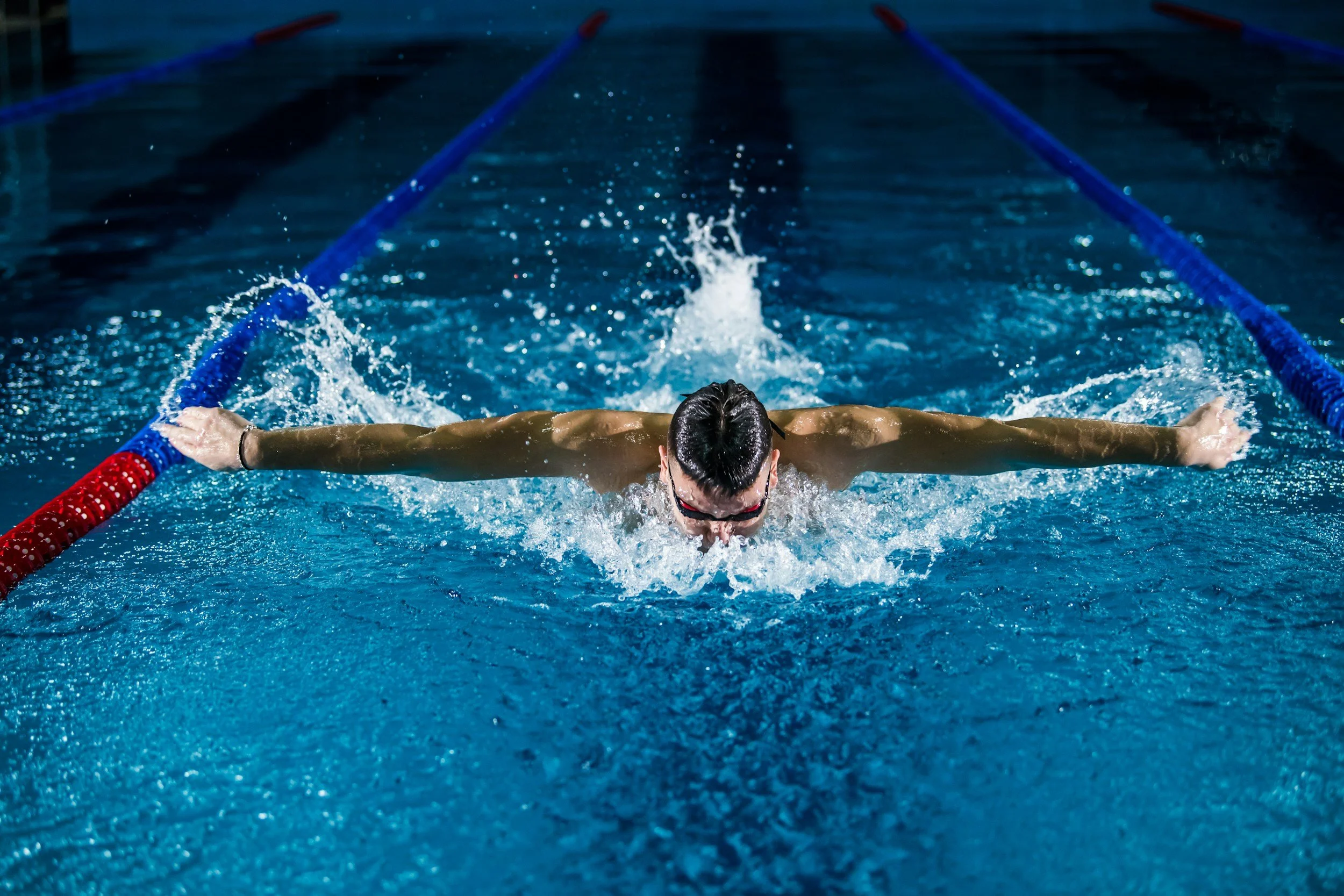 A swimmer doing butterfly stroke in a swimming pool.