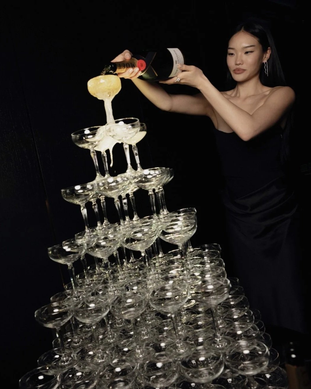 Model pouring a large champagne tower at a corporate awards show.