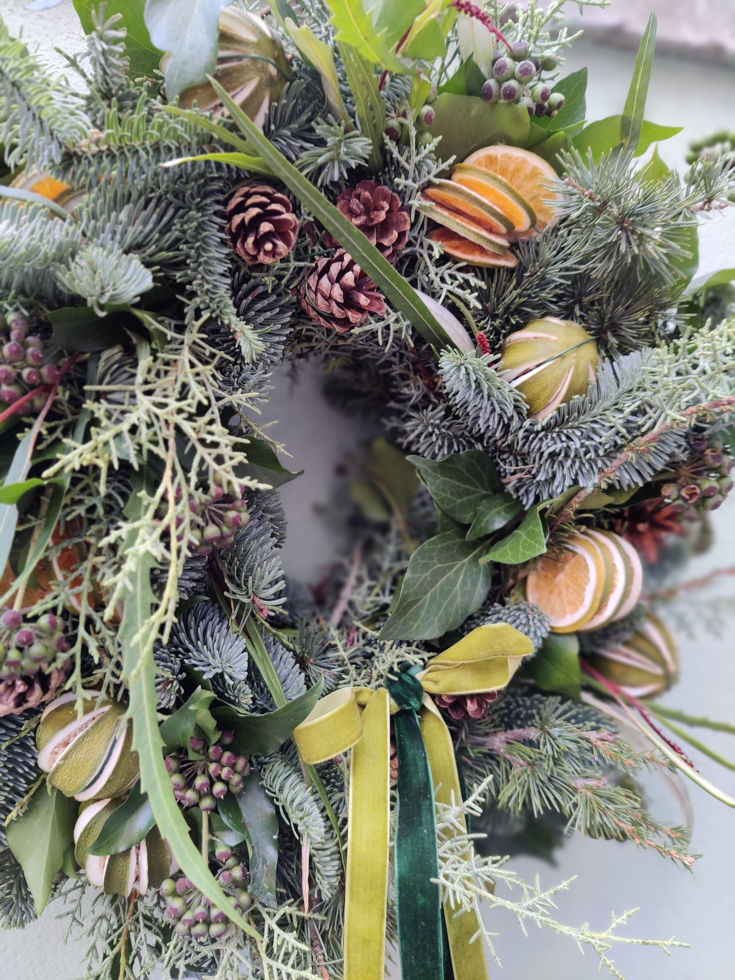 Close up of a festive wreath made from seasonal foliage and finished in velvet ribbon