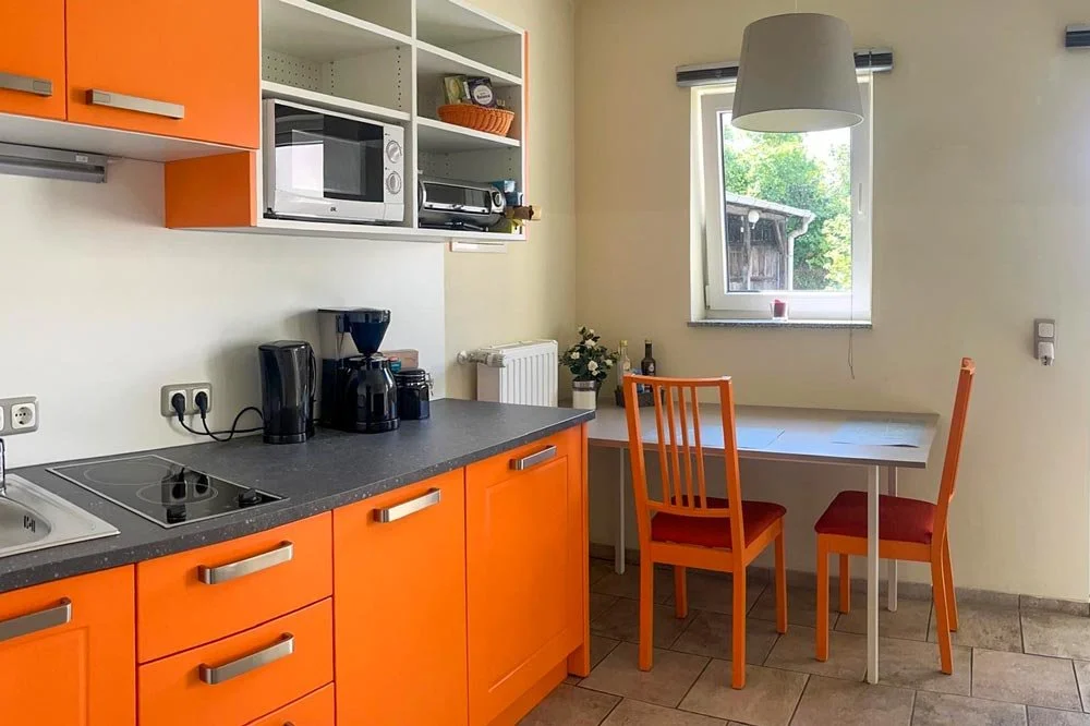  Apartmentküche in Orange mit Essplatz und Kaffeemaschine 