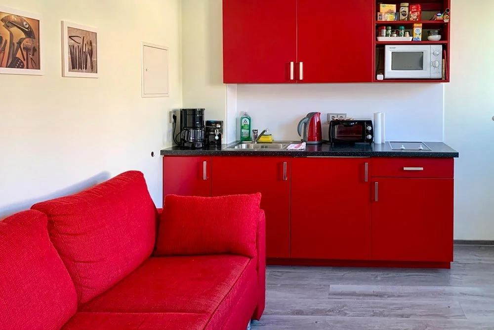  Küchenbereich mit rotem Sofa und Esstisch im Apartment 