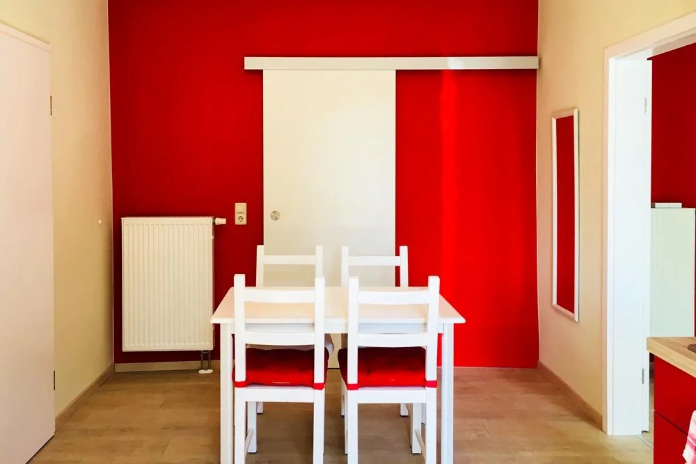  Essbereich mit weißen Möbeln und roten Akzenten 