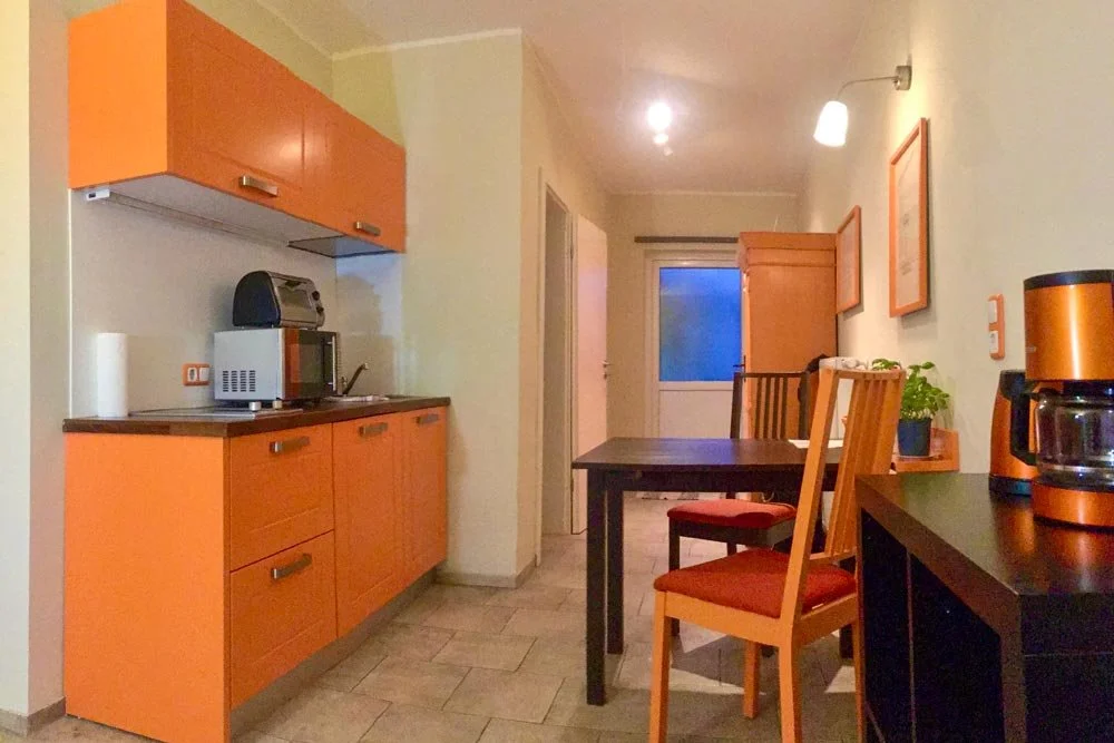  Küche mit Essbereich im 2-Raum-Apartment mit orangefarbenen Fronten 