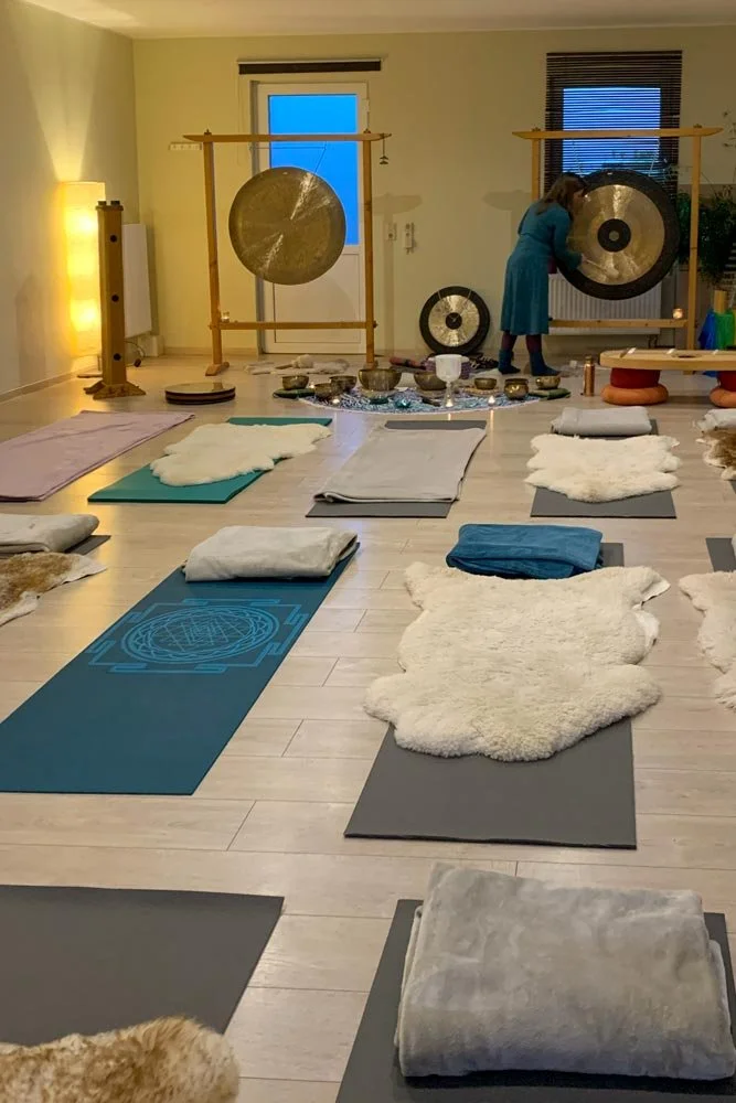  Ein atmosphärischer Raum für Seminare und Gruppenarbeit. Zu sehen sind Yogamatten, Felle, Klangschalen und große Gongs, die auf einen Raum für Yoga / Bewegung oder Klangtherapie hinweisen. 