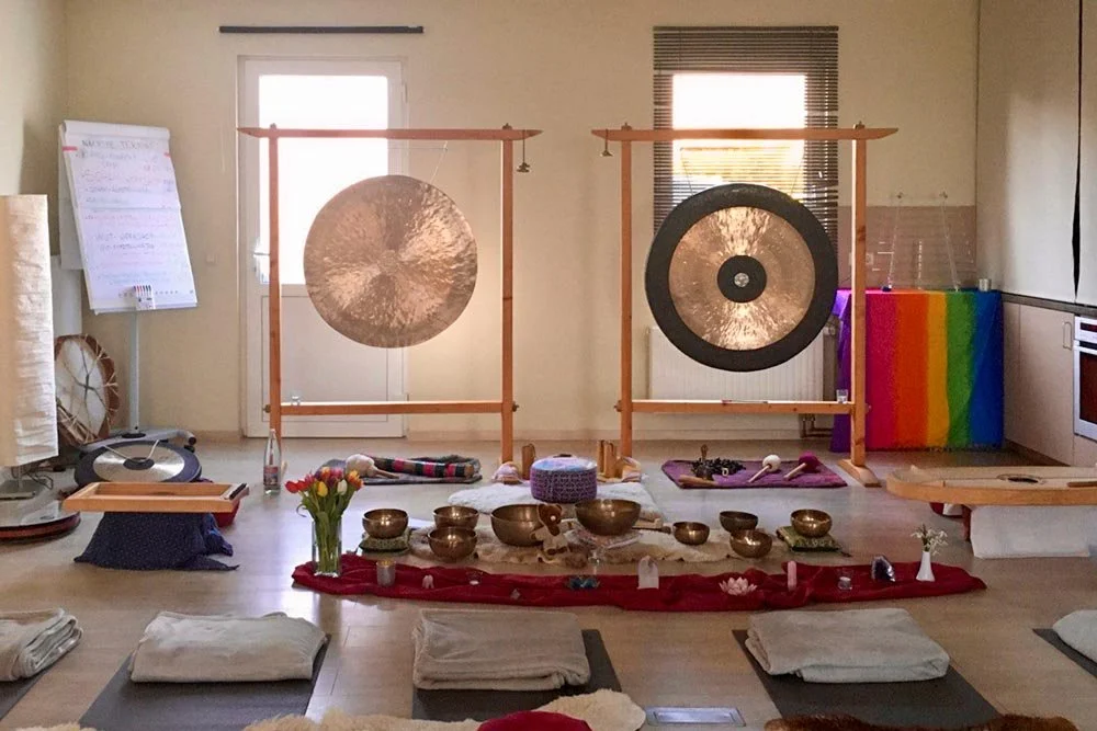  Breiter Blick auf den zentralen Veranstaltungsraum mit zwei großen Gongs, Klangschalen, Meditationsunterlagen und Tulpen. Ein meditativer Creative Space für Körperarbeit und Retreats. 