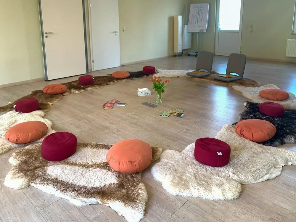  Raum für Austausch und Selbsterfahrung: Meditationskreis mit Schaffellen und Kissen für Gruppenarbeit. 