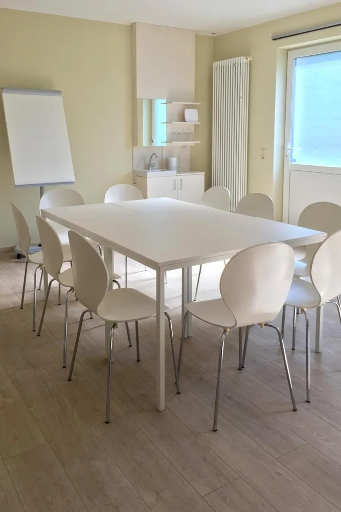  Moderner Konferenzraum und Meetingraum mit weißem Tisch und Flipchart, perfekt für Tagesseminare. 