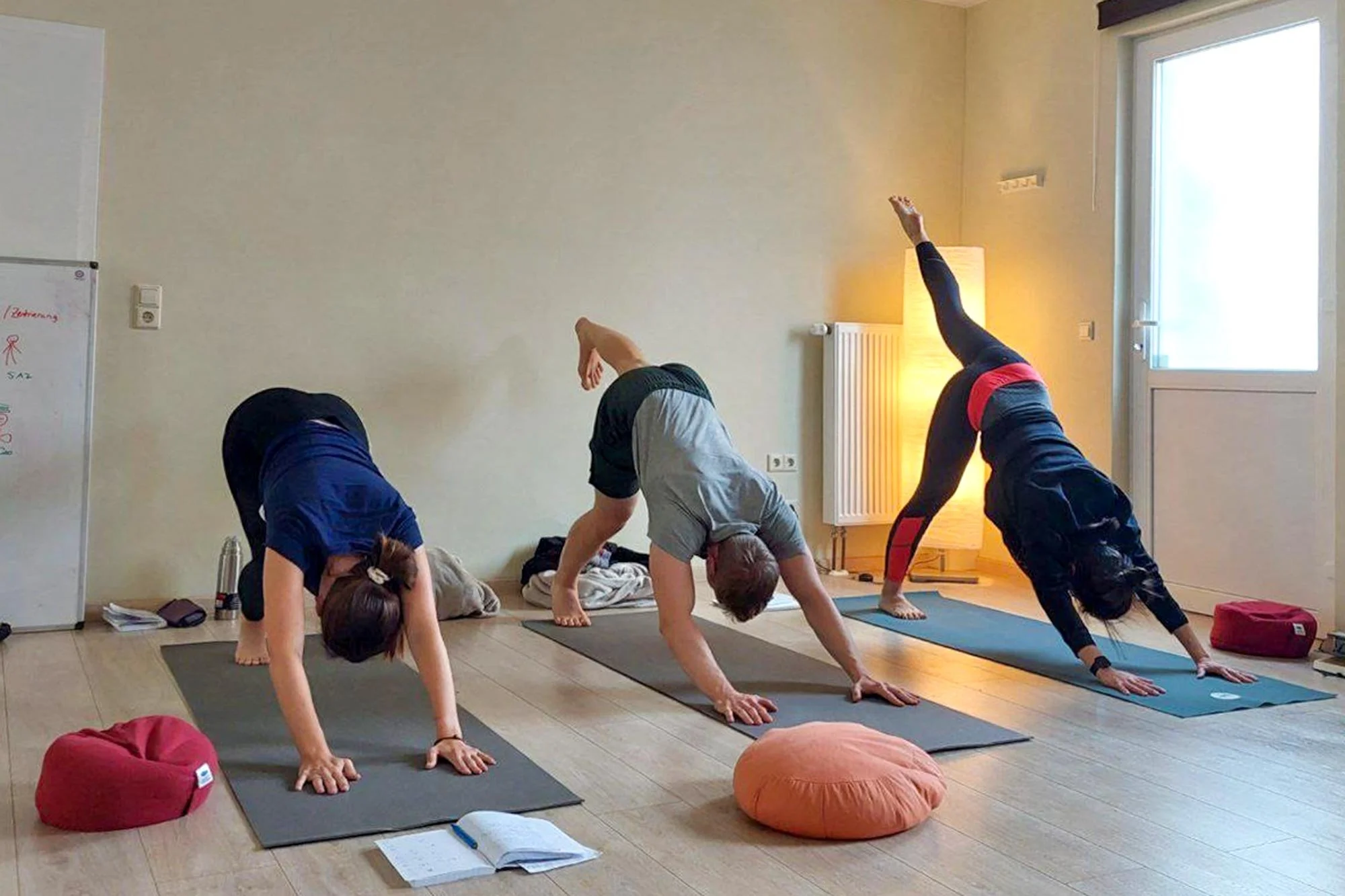 Yoga für Männer und Frauen in der Senfbude: Teilnehmer üben den herabschauenden Hund in einer kleinen, individuell betreuten Gruppe.