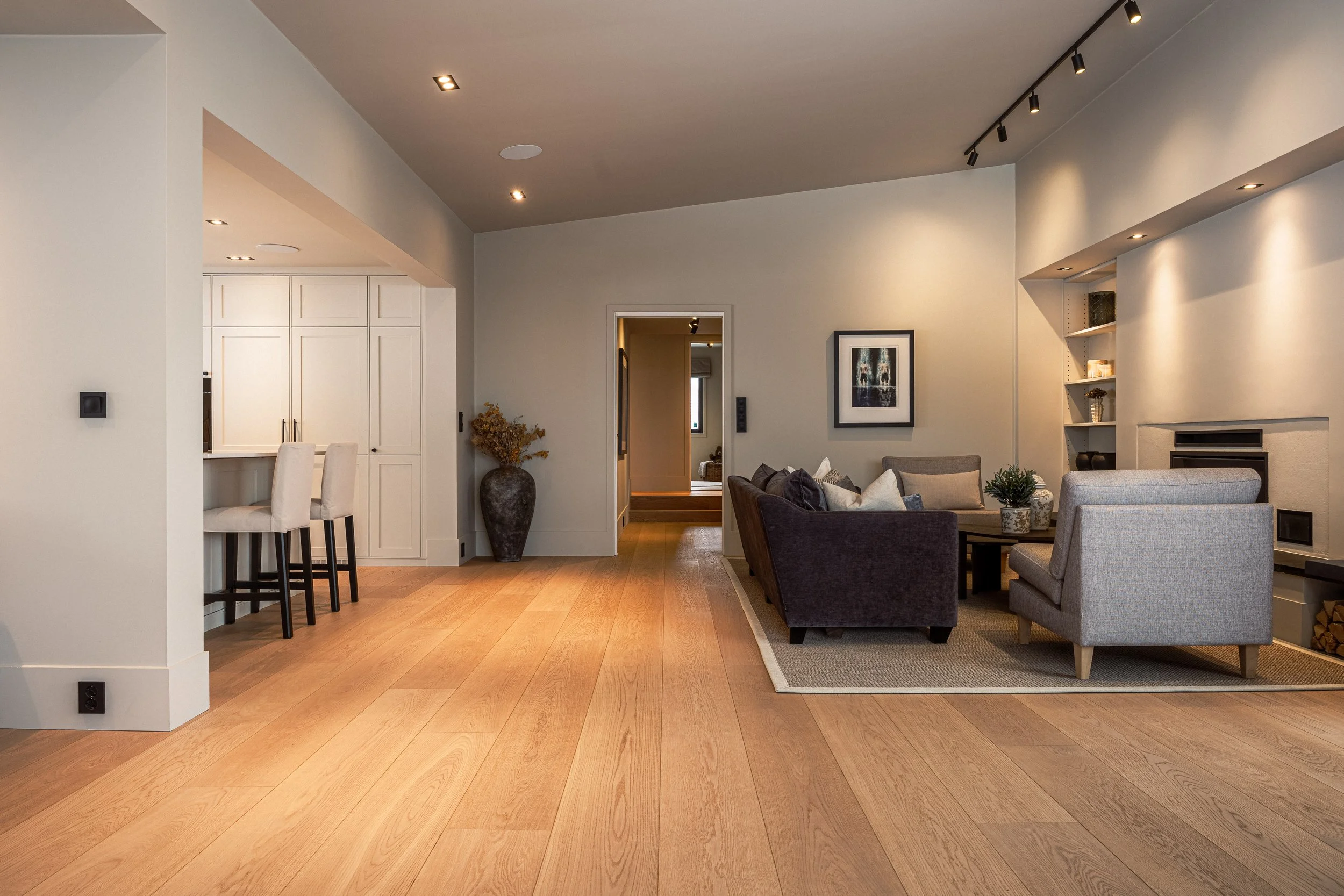 Stue med sofaer, et borstativ, hylle og et bilde på veggen.