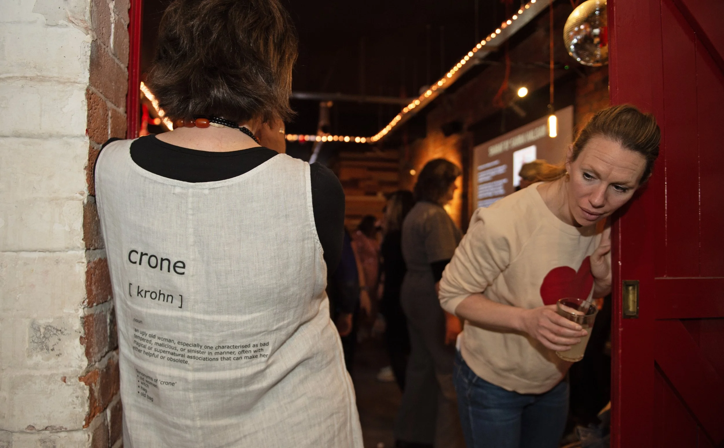 what is a crone? A younger woman checks out Crone Kazza's crone definition shirt made for Crone Club's CroneLines
