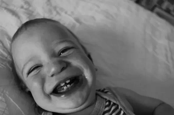 A black and white photo of a smiling baby.