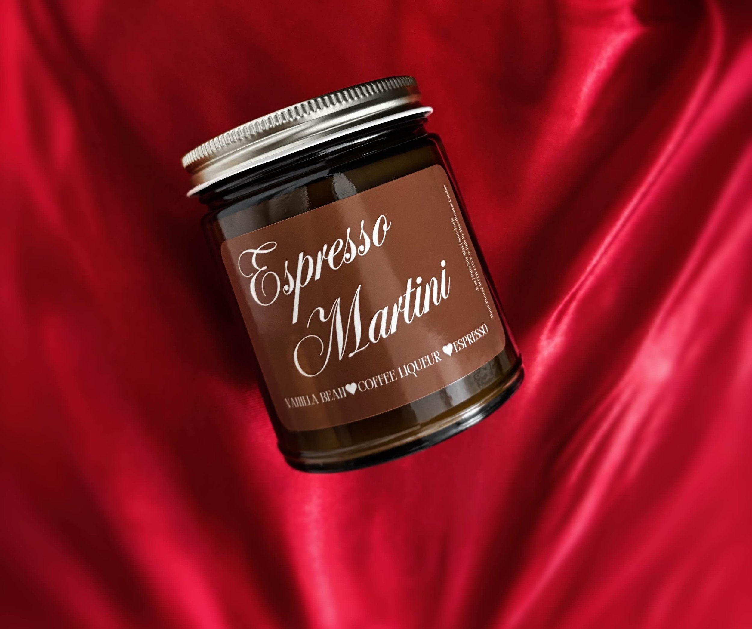 Red satin backdrop. Amber jar candle with the words Espresso Martini written across.