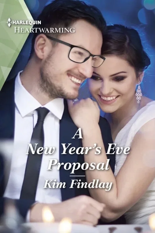 Cover art for author Kim Findlay’s small-town romance novel “A New Year’s Eve Proposal.” A young couple wearing New Year’s Eve outfits lean into each other lovingly.  in front there are a couple of candles.  The blue background is out of focus