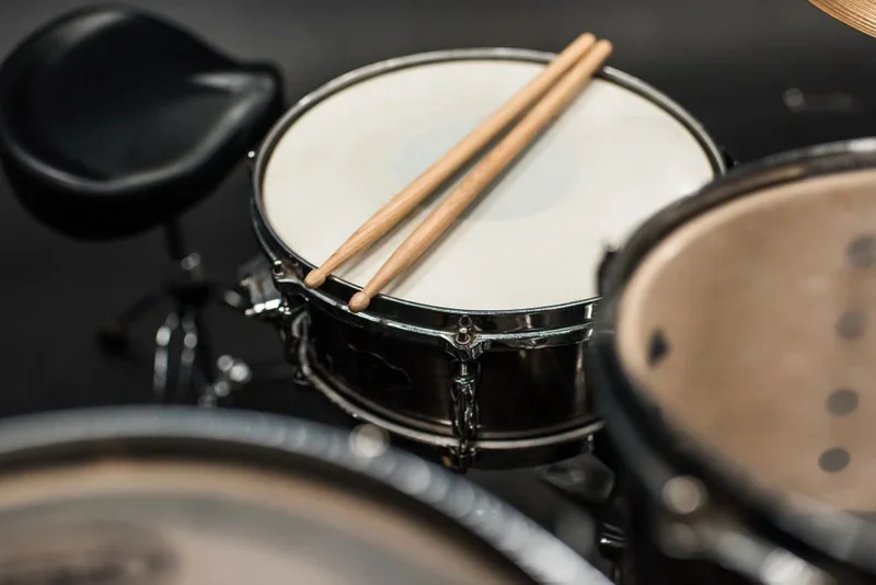 Closeup of a set of drums.  A pair of drumsticks are sitting on the snare drum