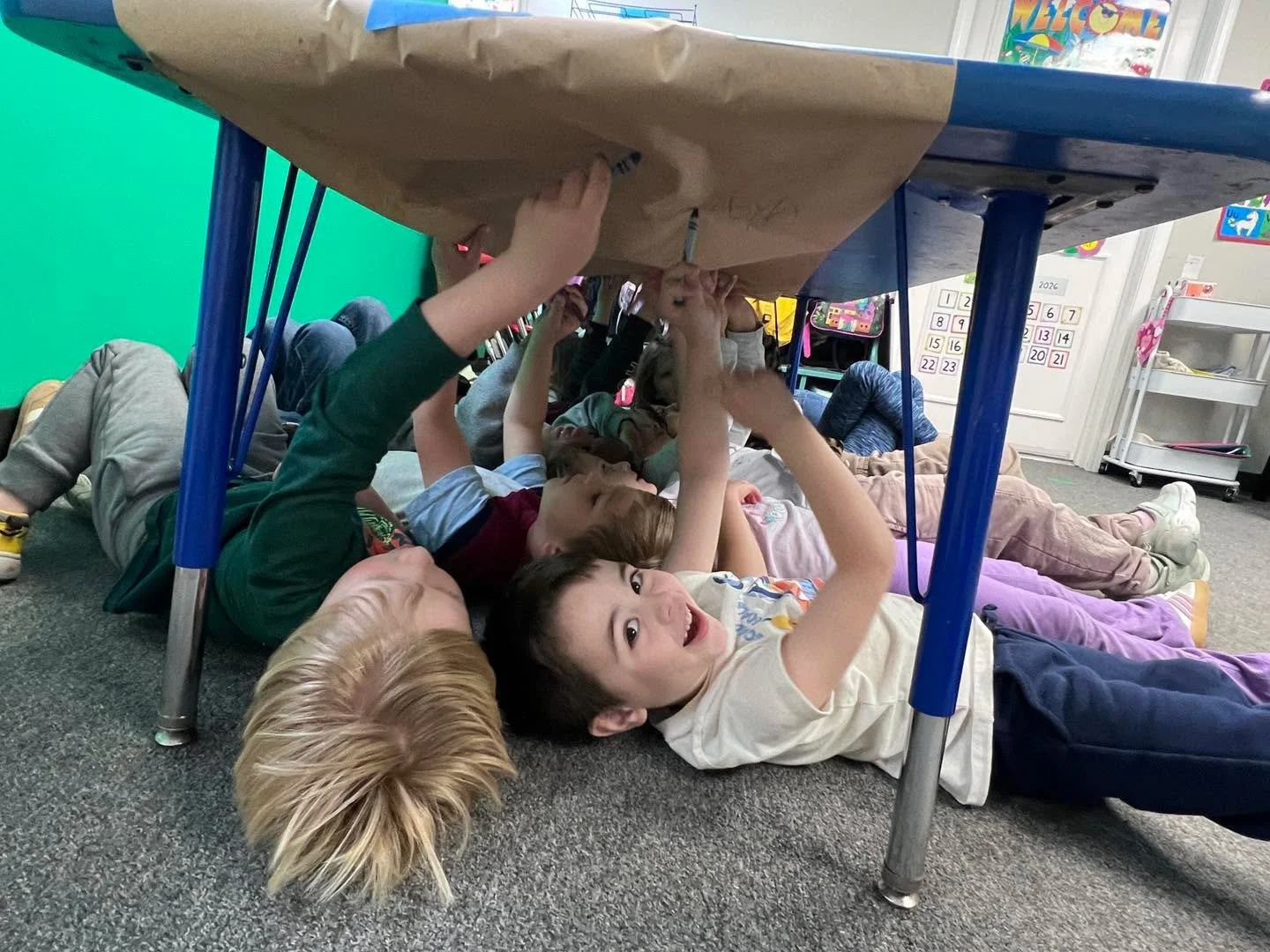 Under the table we went to draw, color and write our name. Not only is it fun, but it strengthens our wrists, encourages a pincer grasp and challenges us to cross our mid-line. Give it a try at home!